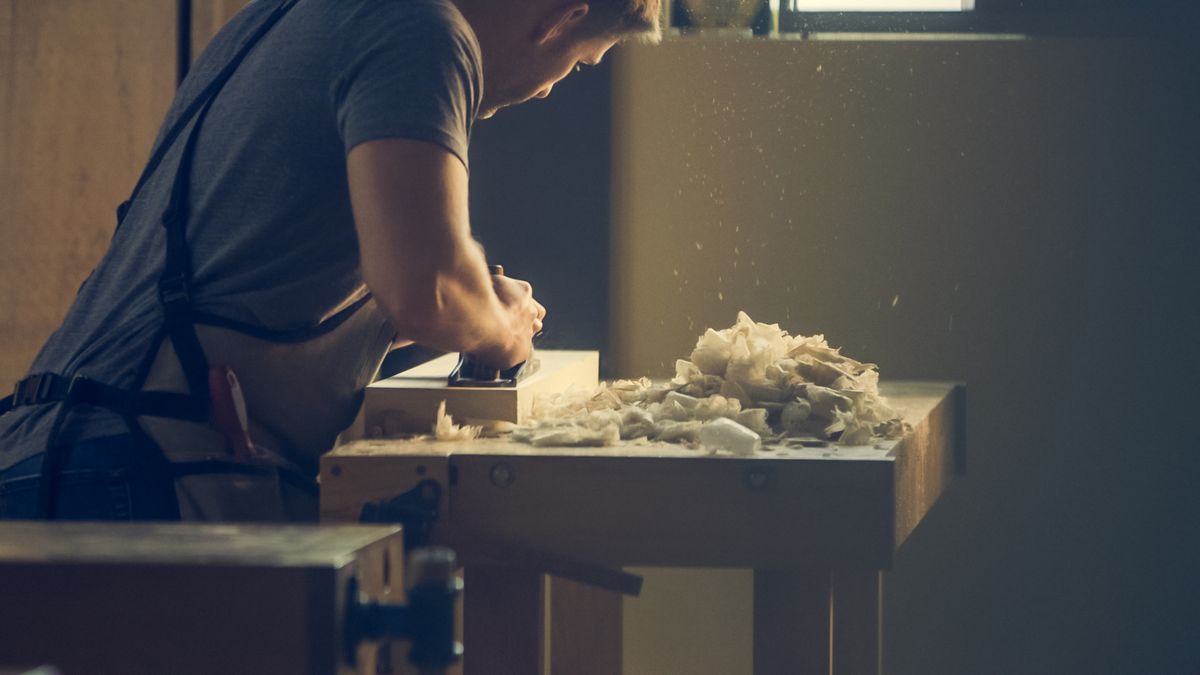 Hand-planing a board, shavings curling off the blade